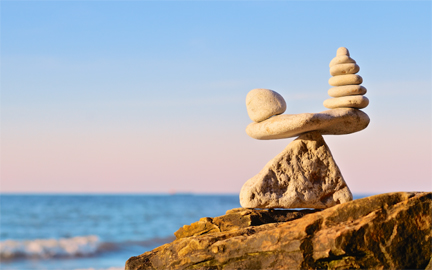 a scale made of rocks and pebbles balance at the ocean side.