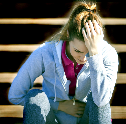 Woman Crouched Over In Menstrual Pain